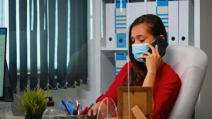 freelancer working talking phone sitting workplace wearing protection face mask coronavirul pandemic woman chatting with remotely team speaking smartphone front computer