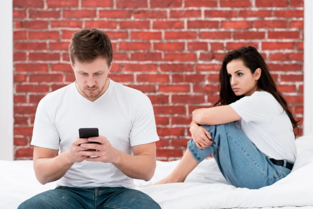 man checking his phone while his girlfriend is angry