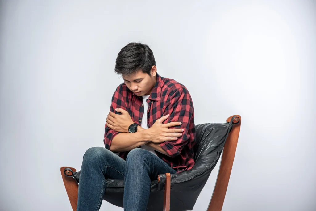 Anxiety Counseling in Gurgaon 23 man striped shirt sits sick sits chair crosses his arms