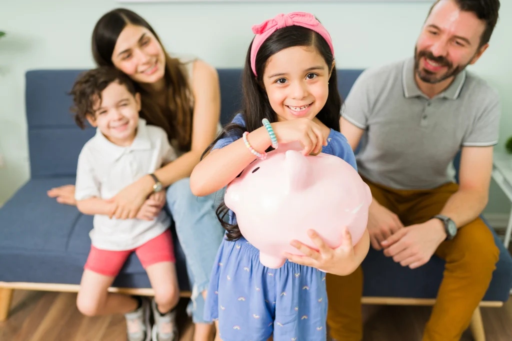 portrait cute little girl putting money pink piggy bank save new toy her her small brother