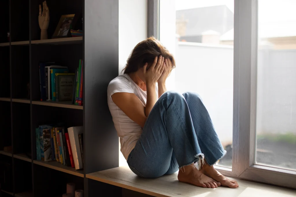 portrait young woman with low self esteem sitting by window home