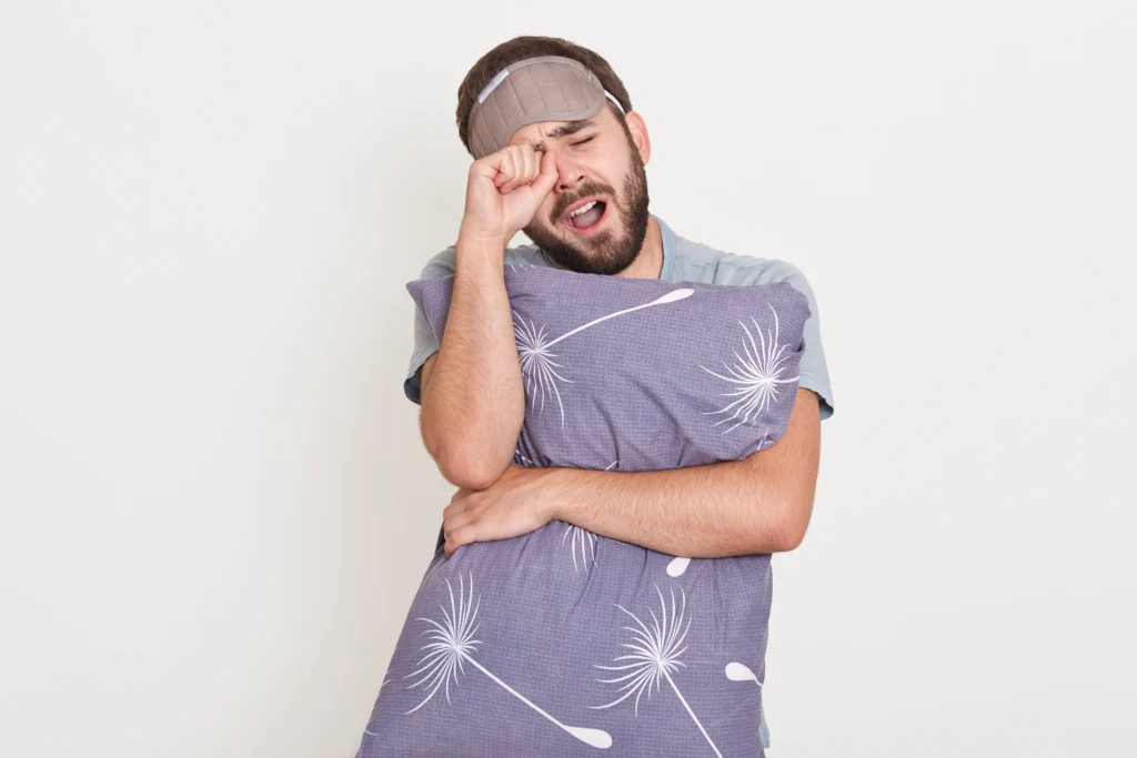 Best Online Sleep Therapy In Gurugram 23 unshaven yawning man posing indoor rubbing his eyes keeping mouth opened holding grey pillow hands guy awaking morning