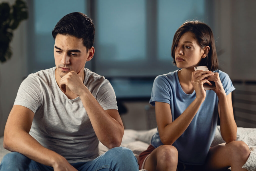 young worried man thinking something while sitting his girlfriend having relationship problems with her