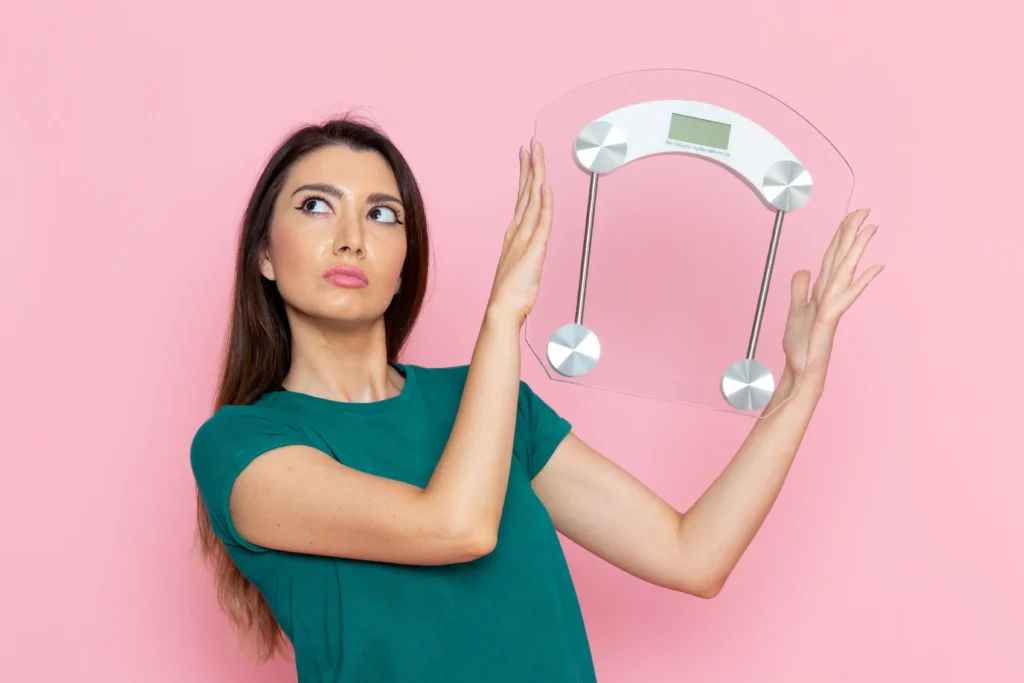 front view young female holding scales pink wall exercise sport workouts athlete waist beauty