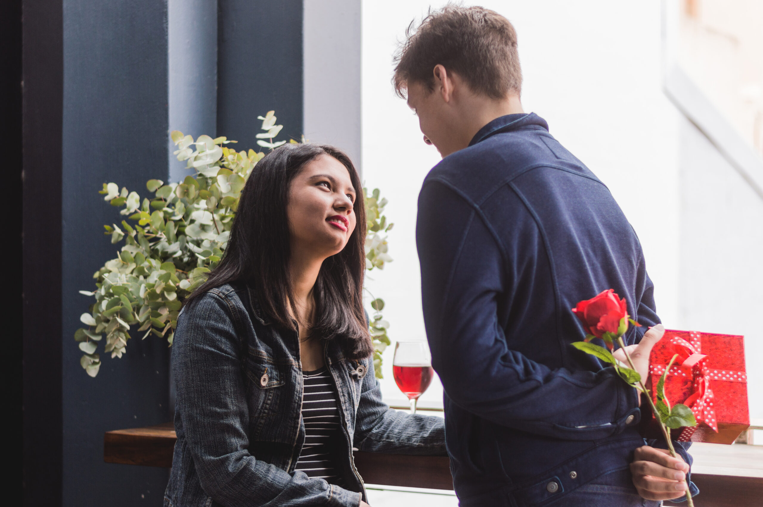 man talking his girlfriend hiding his back gift rose scaled