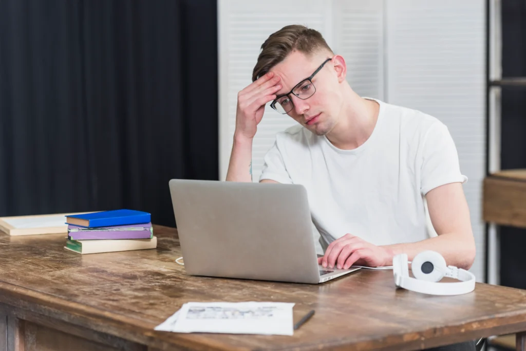 worried young man looking laptop wooden table