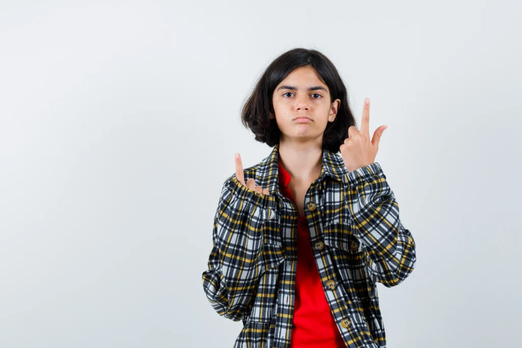 young girl pointing up checked shirt red t shirt looking serious front view