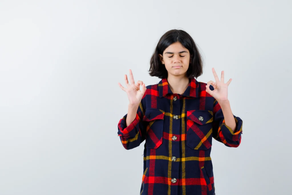 young girl standing meditating pose checked shirt looking calm front view