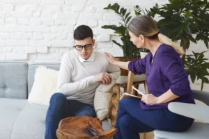 candid shot casually dressed professional woman psychotherapist her fifties touching her young male patient by shoulder while having counseling session expressing sympathy support
