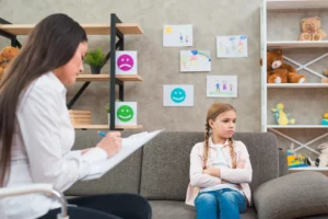 depressed girl sitting sofa with female psychologist writing note clipboard