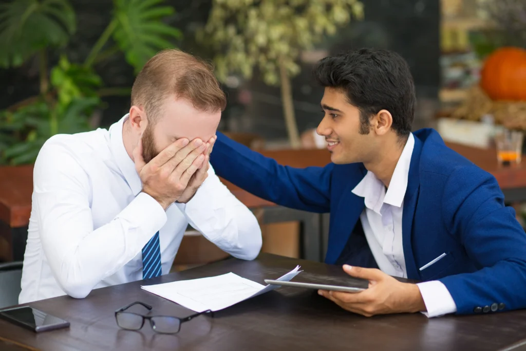 indian businessman supporting colleague stroking his back