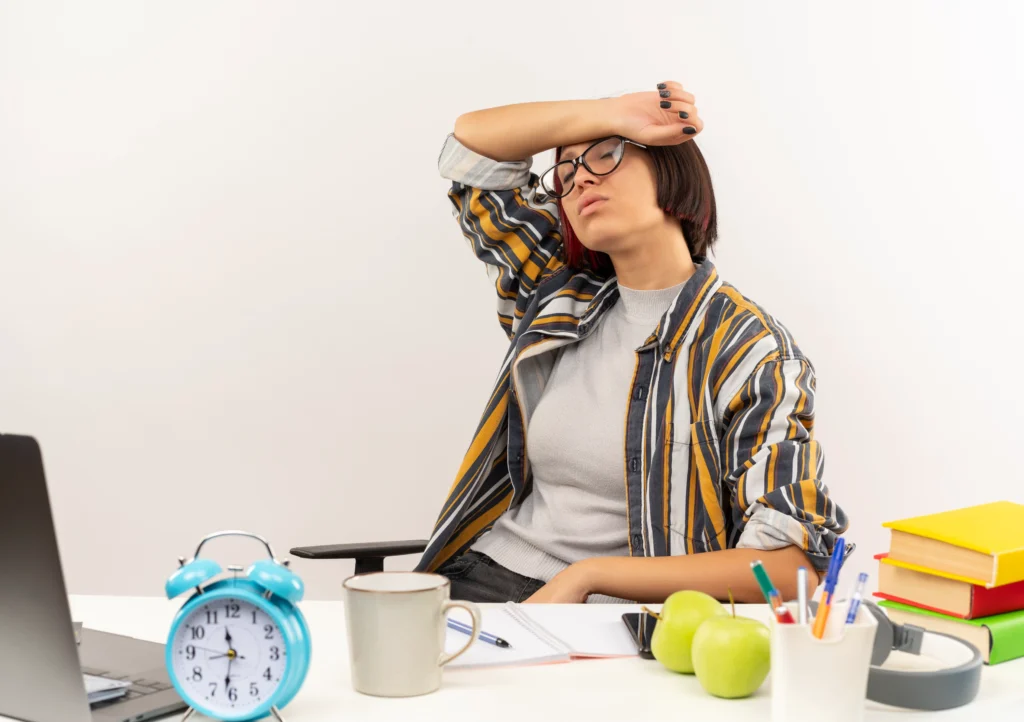 tired young student girl wearing glasses sitting desk with university tools putting arm forehead with closed eyes isolated white background