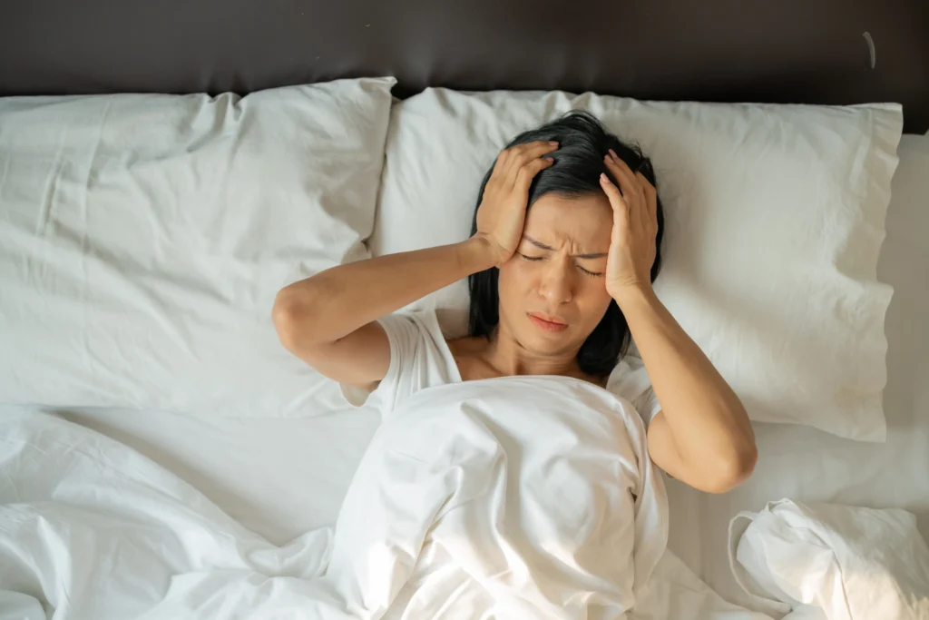 unhappy exhausted mature woman with closed eyes lying bed touching temples close up tired female suffering from headache migraine feeling unwell suffering from insomnia lack sleep