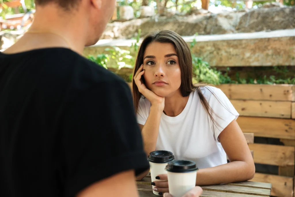 young bored woman sitting drinking coffee with her boyfriend