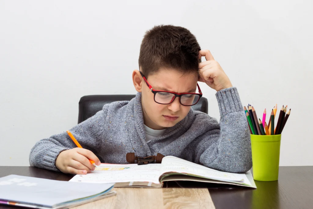 young boy frustrated homework writing home boy studying table kid drawing with pencil