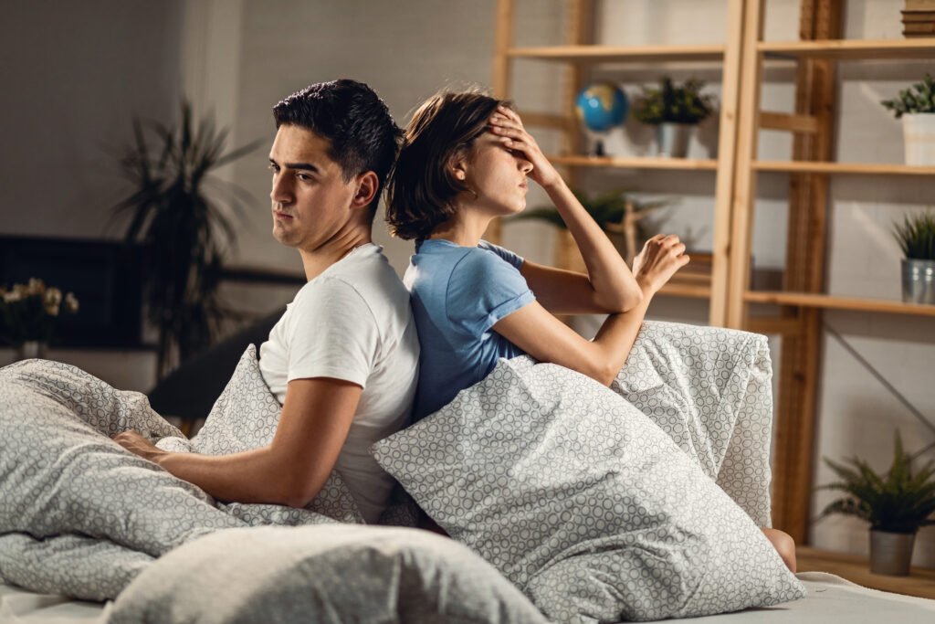 young sad couple ignoring each other while sitting back back bed